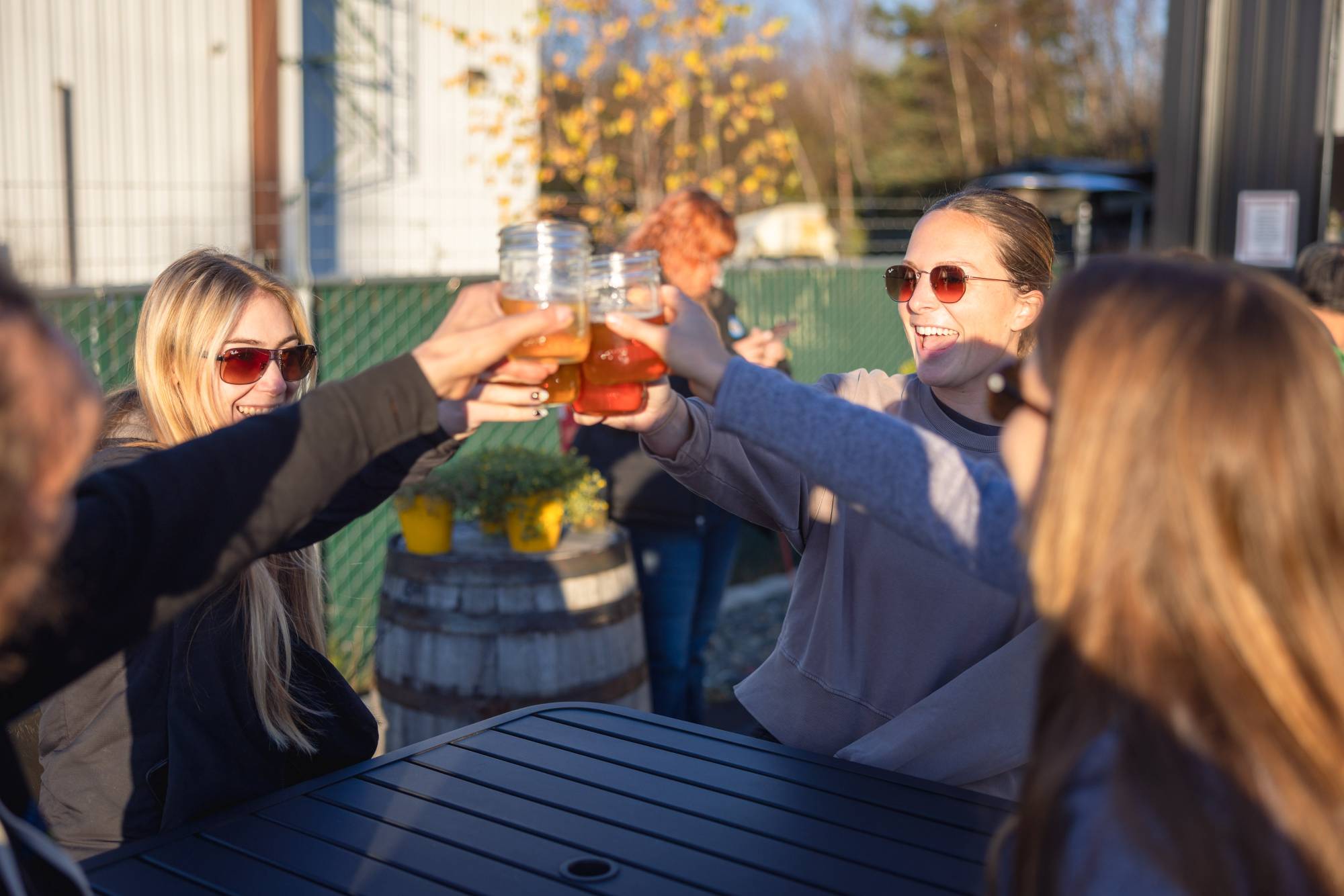 Friends cheering with kombucha mason jars at Zip Kombucha outdoor patio